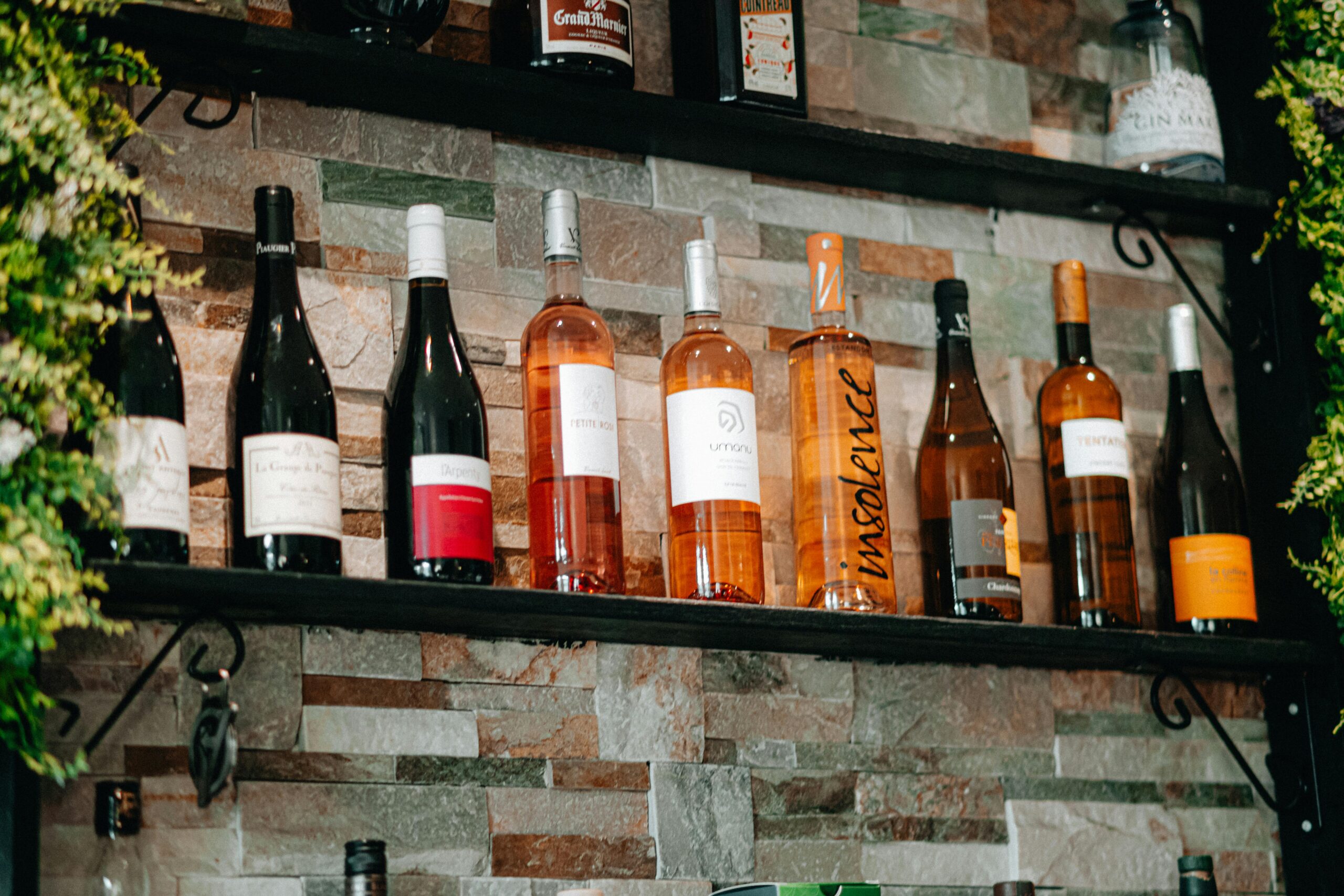 Assorted wine bottles on rustic stone shelves in a cozy setting.