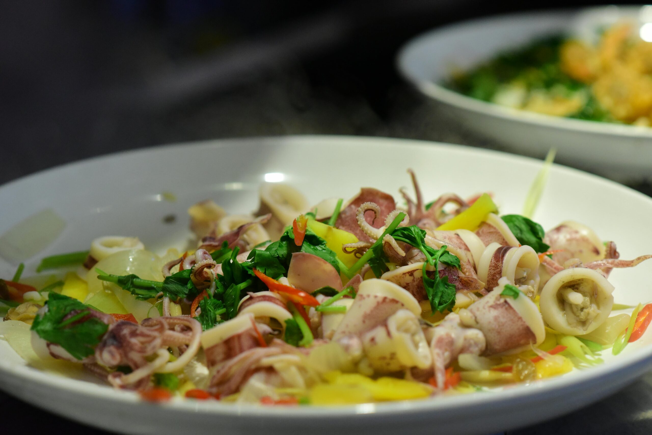 Close-up of a seafood salad featuring fresh squid, garnished with colorful vegetables.