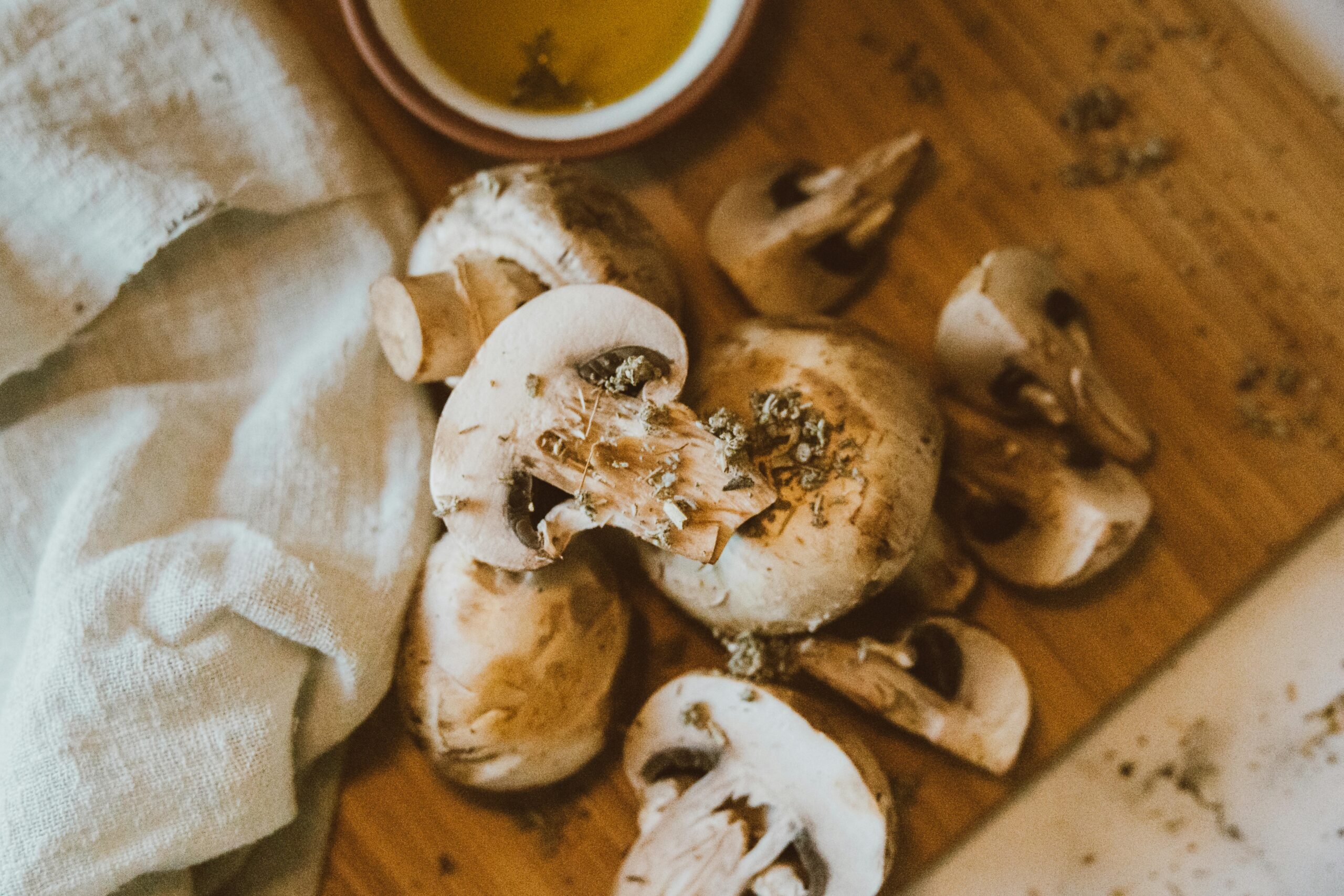 A closeup of fresh mushrooms on a wooden board ready for cooking, next to a cloth.