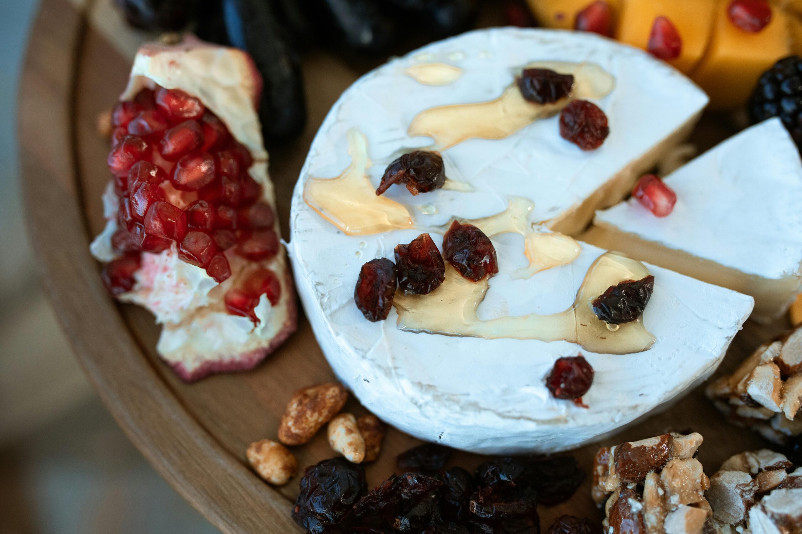 A delectable cheese platter featuring brie, pomegranate, walnuts, and dried cranberries.